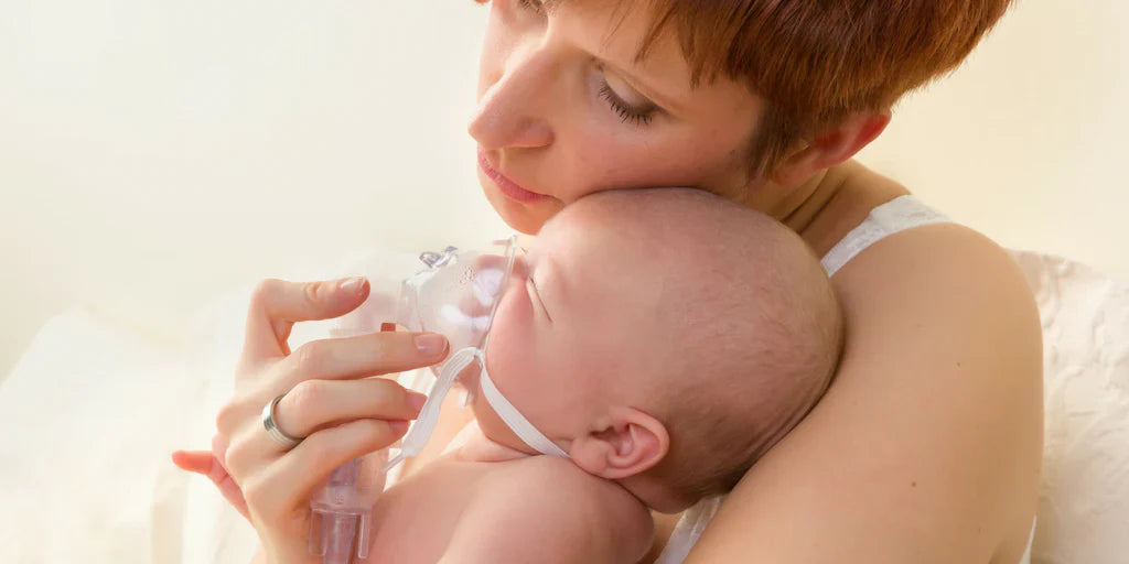 Mutter hält ihr Baby liebevoll im Arm, während das Kind mit einer Atemmaske inhaliert.