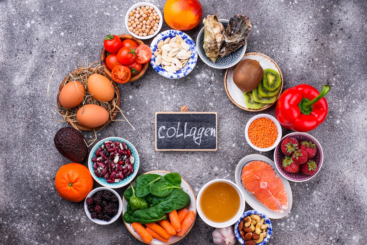Auswahl an Lebensmitteln, die für die körpereigene Kollagenbildung relevante Nährstoffe liefern, darunter Eier, Lachs, Paprika, Beeren, Hülsenfrüchte und Gemüse, arrangiert um ein Schild mit der Aufschrift ‚Collagen‘.