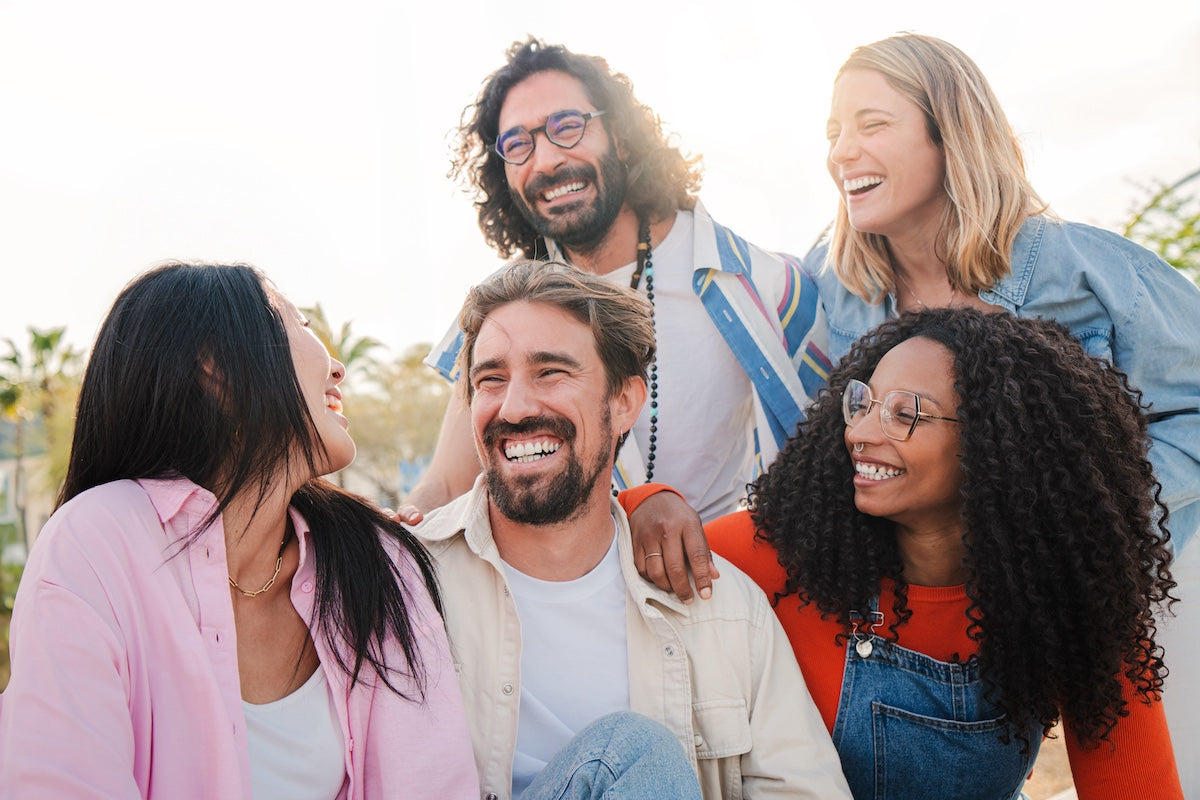 Gruppe junger Erwachsener, die im Freien zusammen lachen und eine fröhliche Zeit verbringen.